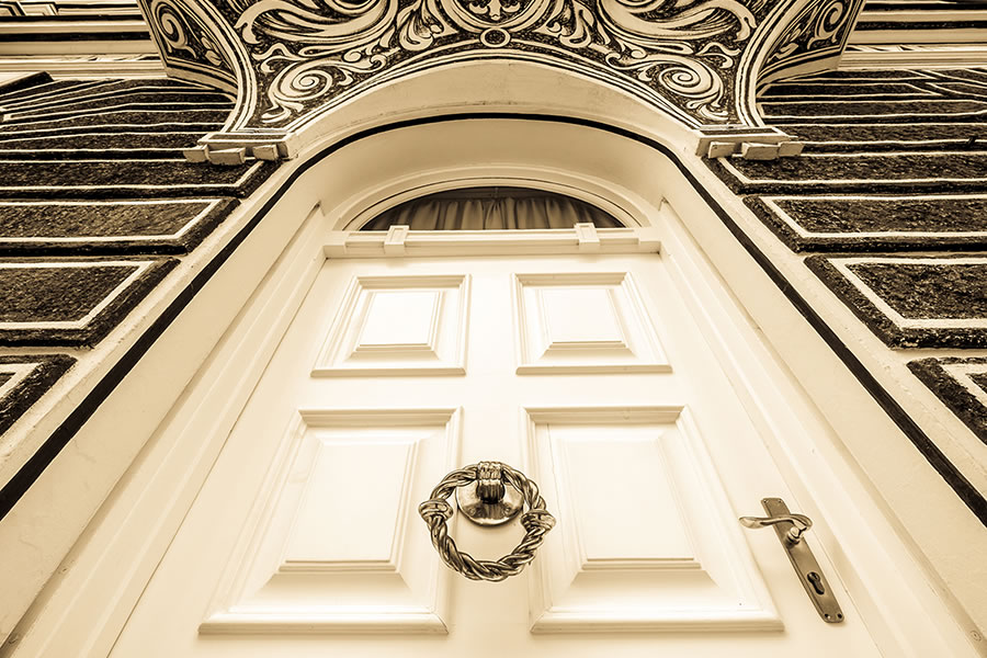 Perspektivischer Blick von unten auf historische, elfenbeinfarbene Tür